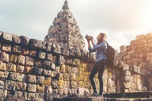 giovane turista attraente del fotografo con lo zaino che viene a scattare foto all'antico tempio di phanom rung in tailandia.