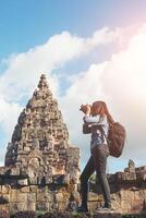 giovane turista attraente del fotografo con lo zaino che viene a scattare foto all'antico tempio di phanom rung in tailandia.