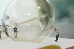 concetto di idea creativa - fotografo in miniatura con lampadina vintage su quaderno di carta aperto foto