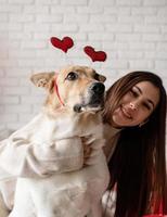 san valentino, festa della donna. giovane donna bruna caucasica seduta nel letto che celebra il giorno di San Valentino lavorando su laptop online foto