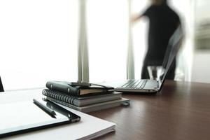 documenti aziendali sul tavolo dell'ufficio con smart phone e tavoletta digitale e uomo che lavora in background foto