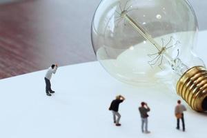 concetto di idea creativa - fotografo in miniatura con lampadina vintage su quaderno di carta aperto foto