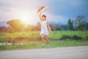 bambina asiatica e padre con un aquilone che corre e felice sul prato in estate nella natura foto