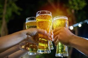 gruppo asiatico di amici che fanno festa con bevande alcoliche a base di birra e giovani che si divertono in un bar a brindare a cocktail e bicchieri tintinnanti