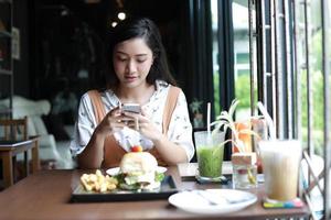 le donne asiatiche scattando foto di hamburger e si sono divertite a mangiare al caffè e al ristorante durante il relax