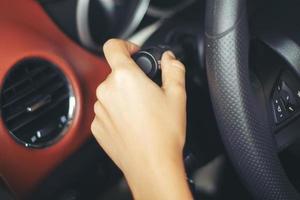 le mani della donna asiatica accendono il pulsante dell'indicatore di direzione, abbottono l'auto, messa a fuoco selettiva a portata di mano foto