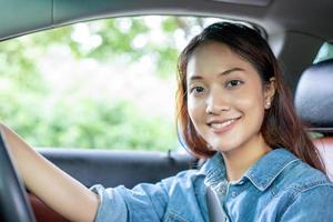 bella donna asiatica che sorride e si diverte. Guidare un'auto su strada per viaggiare? foto