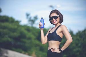 donna sportiva come acqua potabile all'aperto dopo aver corso in una giornata di sole foto