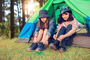 un gruppo di turisti asiatici lega una scarpa vicino alla tenda con felicità in estate mentre è in campeggio foto