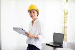 donne asiatiche che ingegnerizzano, ispezionano e lavorano e tengono progetti in ufficio. sta sorridendo felice per il lavoro foto