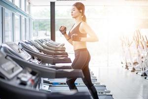 donne asiatiche che corrono scarpe sportive in palestra mentre una giovane donna caucasica sta facendo jogging sul tapis roulant foto