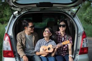 bambina felice con la famiglia asiatica seduta in macchina per godersi il viaggio e le vacanze estive in camper foto