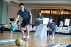 padre che insegna al figlio e alla famiglia giocano a bowling al club di bowling durante il relax foto