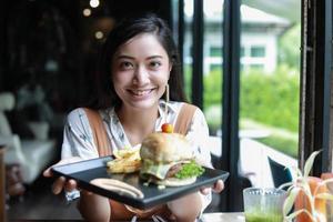 donne asiatiche sorridenti e felici e si divertivano a mangiare hamburger al caffè e al ristorante in tempo di relax foto