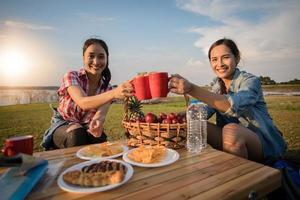 un gruppo di amici asiatici che bevono caffè e trascorrono del tempo a fare un picnic durante le vacanze estive. Sono felici e si divertono in vacanza. foto