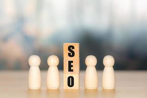 concetto di seo. testo di ottimizzazione dei motori di ricerca o seo su blocco cubo di legno con la figura di legno. ricerca, incremento dei canali di vendita, vendita online, ottimizzazione di siti web e prodotti. foto