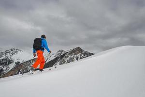 l'uomo con lo sci alpinismo sale verso la vetta foto