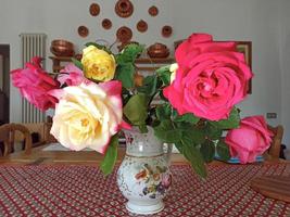 un vaso di rose in un'antica casa in italia foto