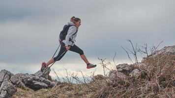 ragazza sportiva salta tra i sassi durante un trekking alpino foto