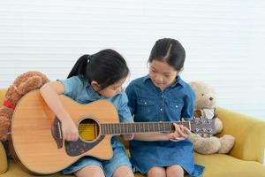 la sorella maggiore insegna a suo fratello minore a suonare la chitarra a casa foto