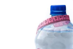 bottiglia di plastica con acqua e nastro di misurazione isolato su bianco foto