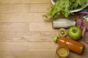 programma di dieta, metro a nastro, acqua, dieta di frutta fresca sul pavimento di legno. foto