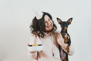 ragazza felice che dà una torta fatta in casa al suo cane, al chiuso foto