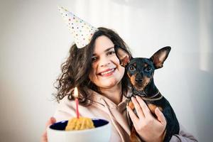 ragazza felice che dà una torta fatta in casa al suo cane, al chiuso foto