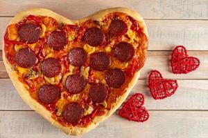 pizza ai peperoni a forma di cuore su fondo di legno. regalo di San Valentino. foto