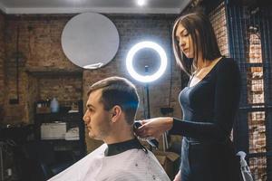 bella donna parrucchiere che taglia i capelli del cliente con le forbici in un negozio di barbiere. concetto di pubblicità e parrucchiere