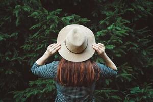 donna con un cappello di paglia e vestito su uno sfondo di alberi verdi foto