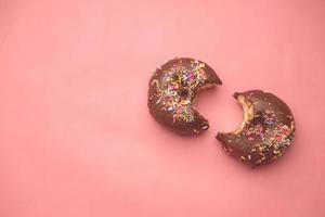 vista dall'alto di ciambelle al cioccolato mangiate a metà su rosa foto