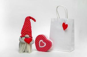 mockup di un pacchetto bianco con uno gnomo e una confezione regalo su sfondo chiaro. idea San Valentino foto