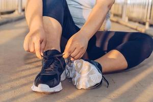 donna che lega i lacci delle scarpe su una passerella foto