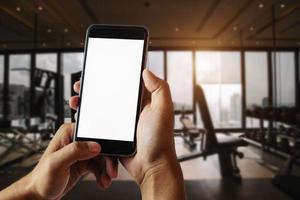 una mano d'uomo che tiene il dispositivo smart phone nella sala fitness foto