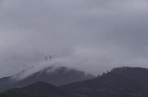 turbine eoliche che sfruttano l'energia del vento avvolte nella nebbia sulle colline costiere liguri foto