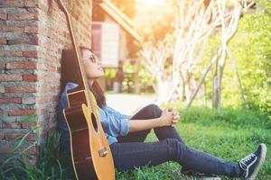giovane ragazza hipster seduta a suonare una chitarra e cantare. foto
