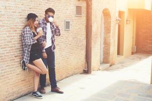 ritratto di giovane coppia hipster in posa con il suo ragazzo in possesso di una tazza di caffè godendo la vacanza insieme sullo sfondo del muro di mattoni. foto