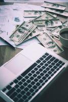 sede di lavoro del commerciante. il tavolo coperto da banconote, tastiera e grafici finanziari. funzionamento finanziario aziendale. foto