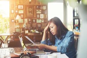 giovane donna seduta in un caffè con il suo laptop, stressante per il lavoro. foto