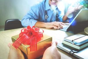 regalo che fa una mano o una squadra del paziente che fa un regalo a un medico sorpreso nell'ufficio dell'ospedale, effetto film filtrante foto