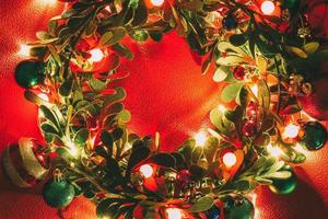 concetto di stagione di saluto. corona di Natale con luce decorativa su sfondo rosso foto