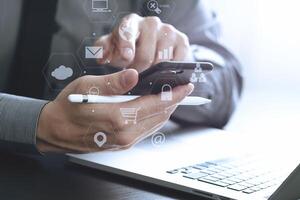 primo piano di uomo d'affari che lavora con il telefono cellulare e la penna stilo e il computer portatile sulla scrivania di legno in un ufficio moderno foto