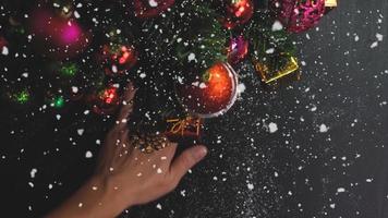 concetto di stagione dei saluti. Impostazione a mano di ornamenti su un albero di natale con luce decorativa foto