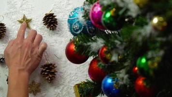 concetto di stagione dei saluti. Impostazione a mano di ornamenti su un albero di natale con luce decorativa foto