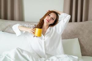 ritratto bella donna sveglia e tenendo tazza di caffè o tazza sul letto