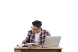 uomo d'affari che scrive sul blocco note mentre è seduto al suo posto di lavoro isolato su sfondo bianco. foto