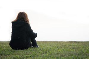 giovane donna seduta sull'erba da sola foto