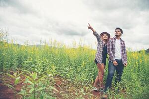 amanti delle coppie di giovani hipster che passeggiano in un campo di fiori, tempo di relax, divertimento con la natura. foto