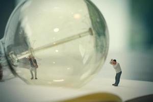 concetto di idea creativa - fotografo in miniatura con lampadina vintage su quaderno di carta aperto foto
